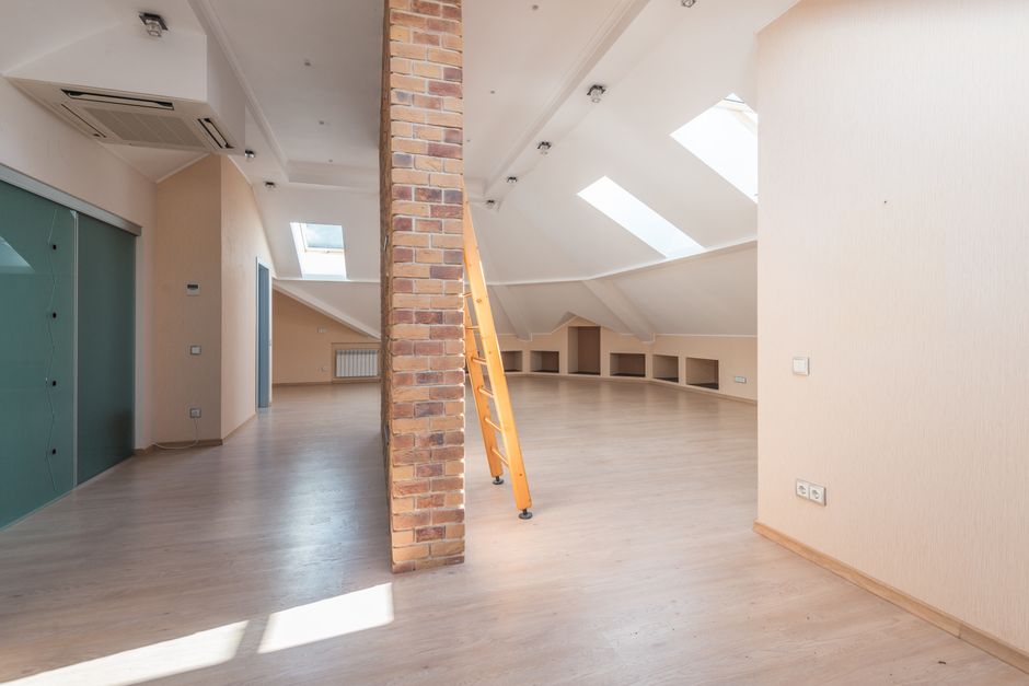 A homeowner examines evenly distributed attic insulation beside roof ventilation baffles and ceiling joists.
